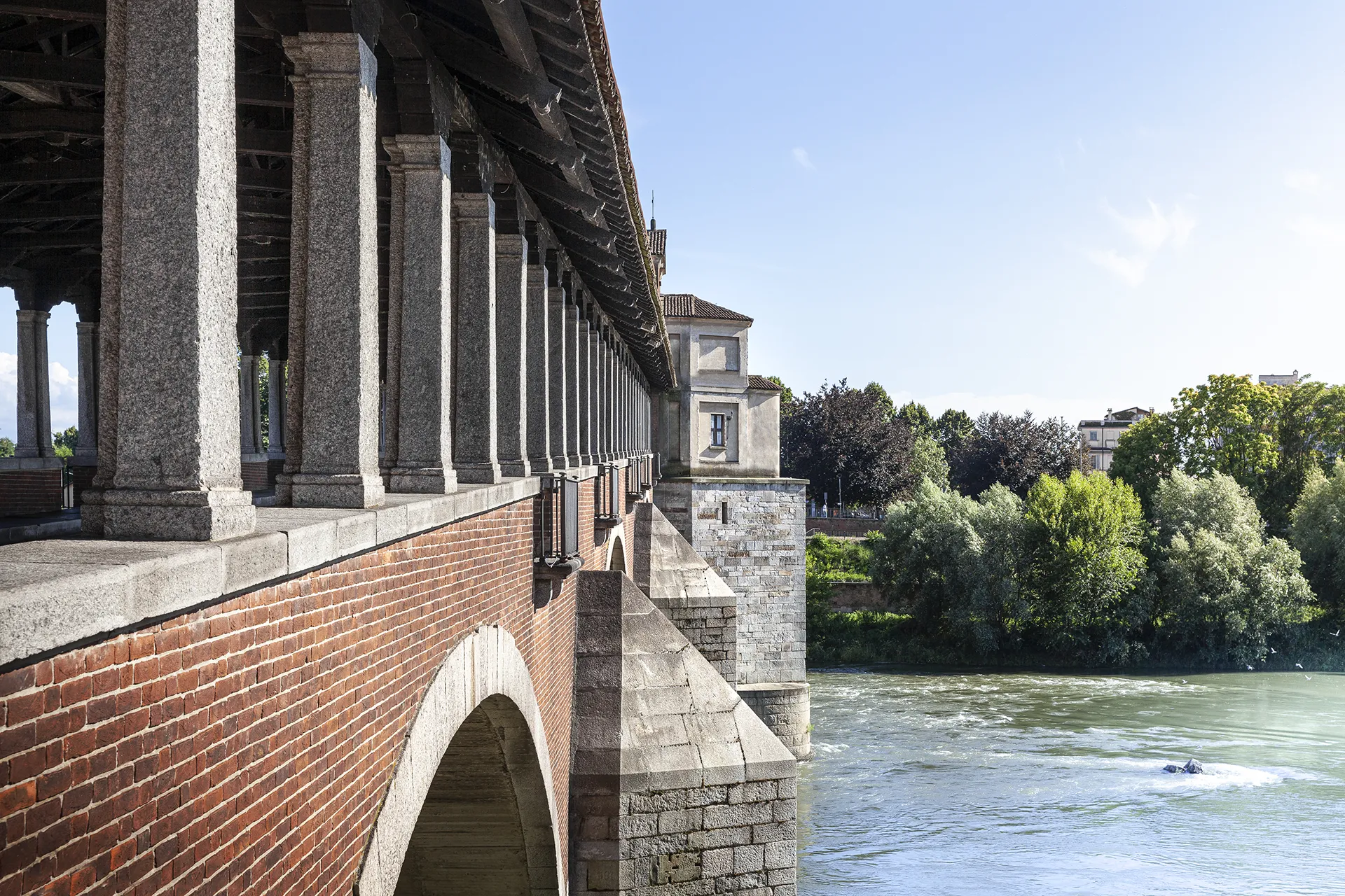 Il Ponte Coperto di Pavia visto dalla riva, con i portici sul fiume