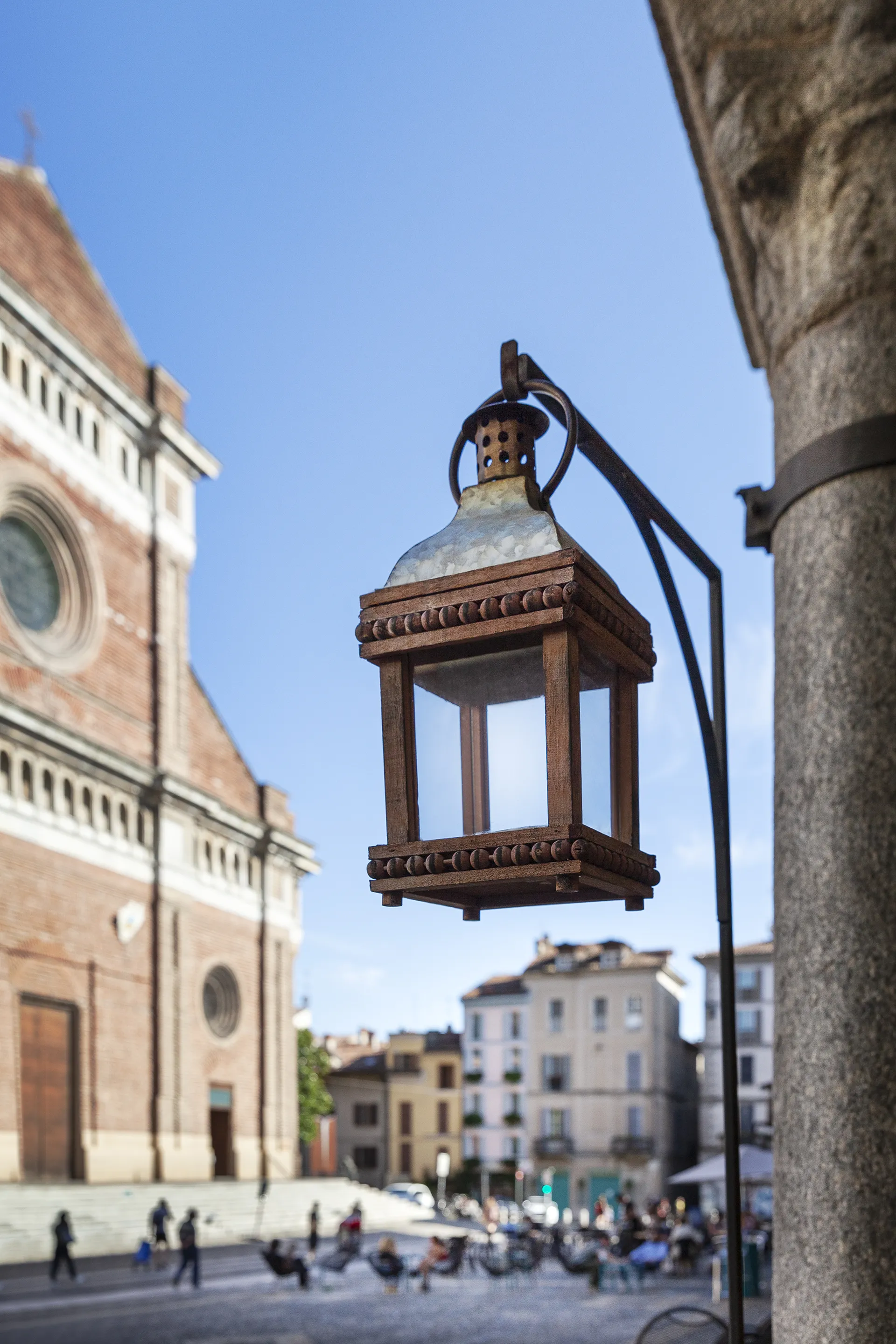 Una lanterna in ferro e la piazza del Duomo con i tavolini